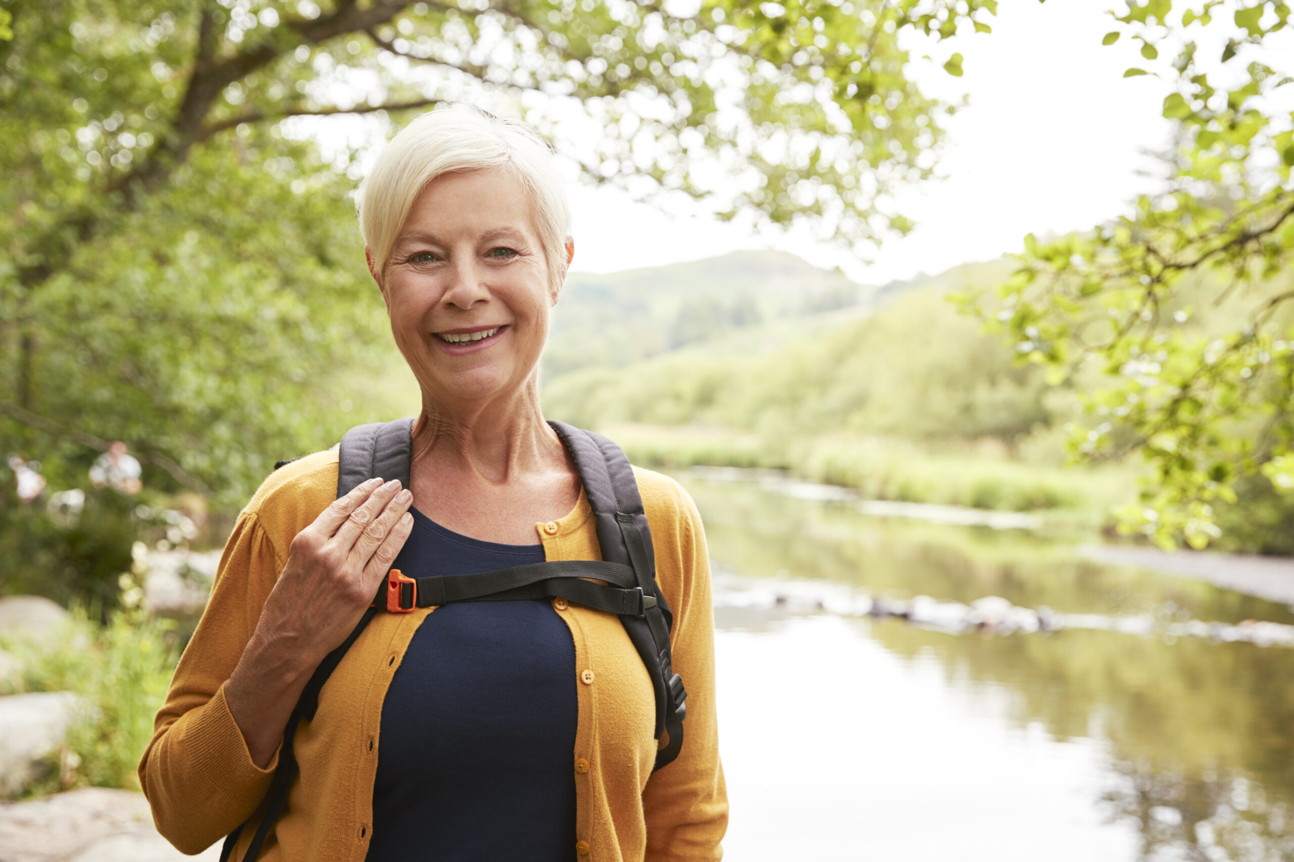 Blonde ältere Frau mit orangener Bluse in der Natur