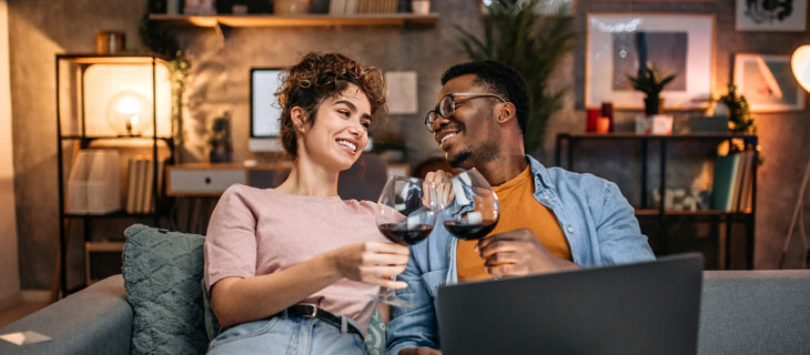 Mann und Frau stoßen auf Sofa mit Rotwein an