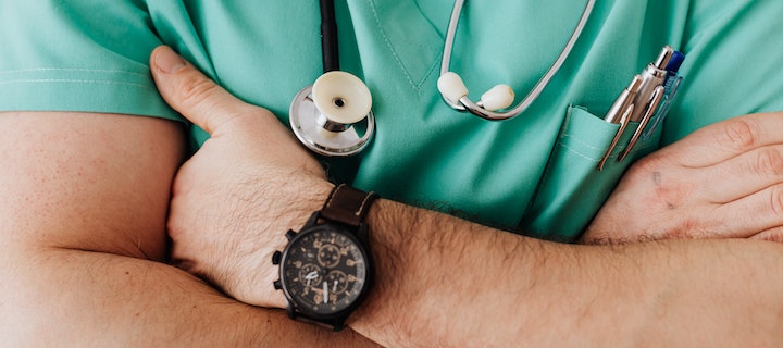Mann im grünen Arztkittel mit Armbanduhr