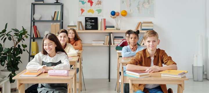 Junge Kinder sitzen auf Stühlen in Klassenraum